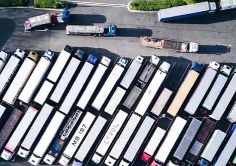  A logistics company parking lot with dozens of trucks. 